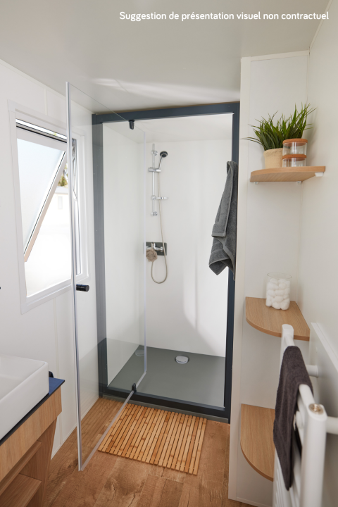 Modern shower with glass door and wooden accents in a stylish glamping bathroom with toiletries.