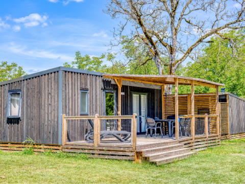 Homeflower Premium met airco: Houten chalet met terras, tuinmeubilair en frisse groene omgeving.