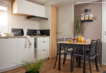 Cocina glamping moderna con mesa de comedor, cuatro sillas, desayuno, jugo y luz natural de ventana.