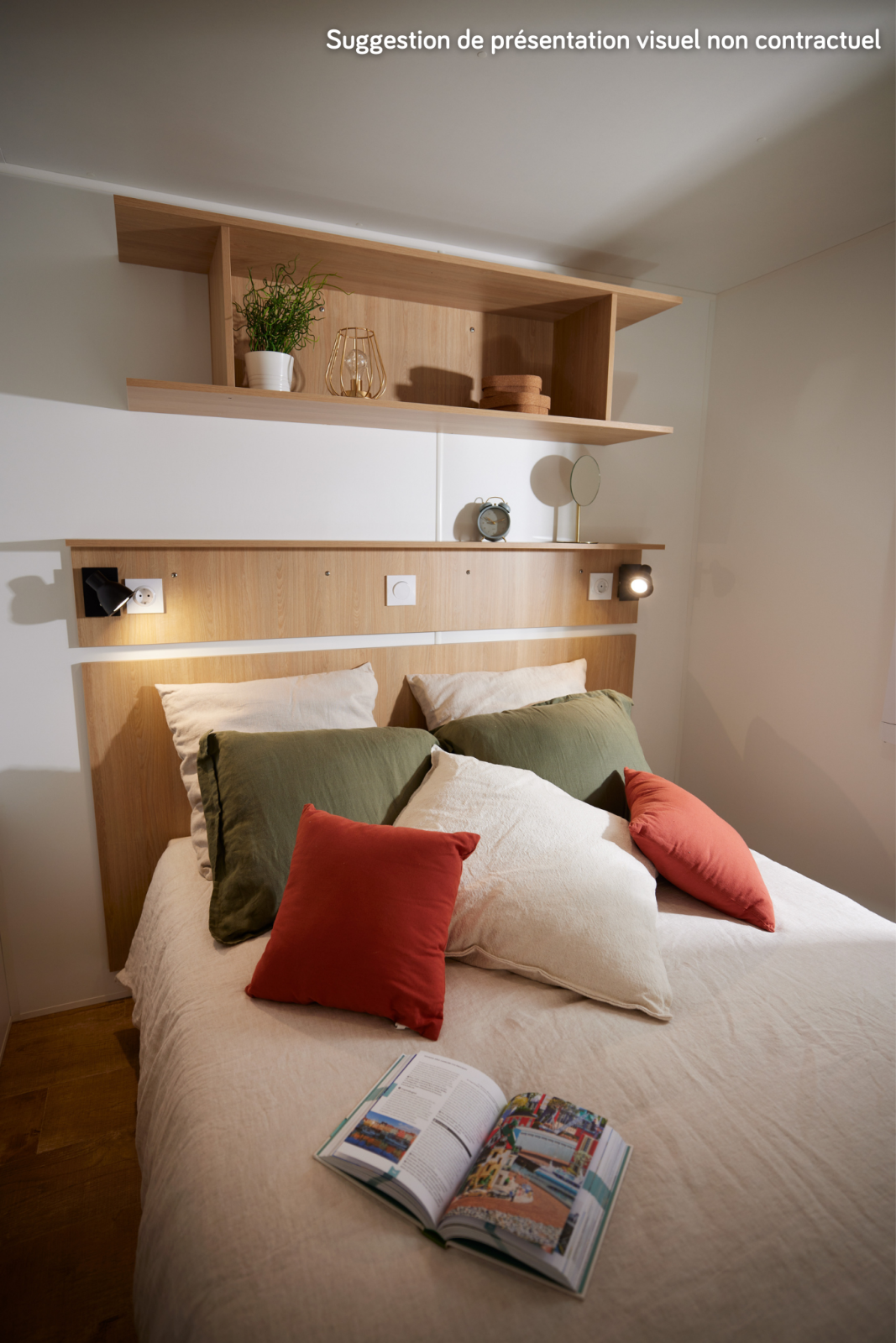 Knusse glamping slaapkamer met tweepersoonsbed, kleurrijke kussens, houten planken en open boek.