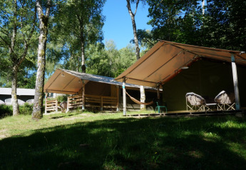 Foto all'aperto di tenda safari Freeflower Standaard con veranda, sedie e amaca in un bosco.