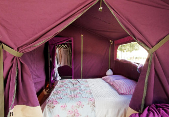 Gezellige safari tent met tweepersoonsbed en kledingrek bij Freeflower Standaard, Flower Camping La Plage, Frankrijk.