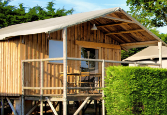 Vue extérieure de la Cabane Lodge Standaard, une cabane en bois sur pilotis avec terrasse et verdure.