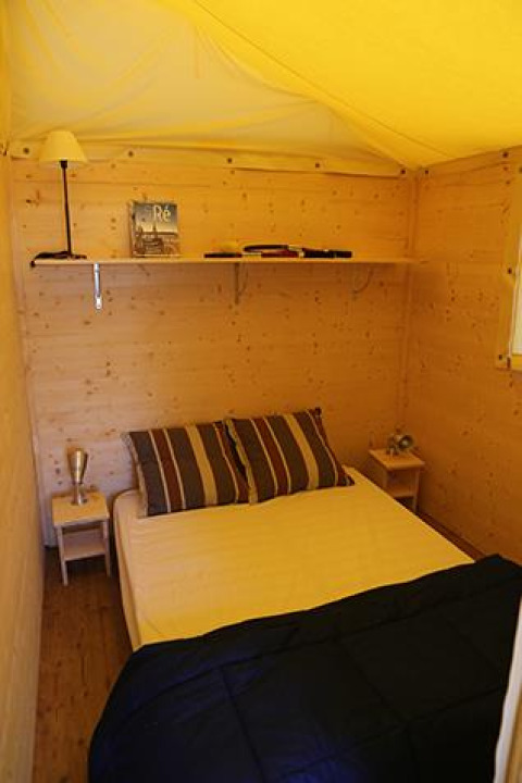 Interieur van de Cabane Lodge Standaard bij Flower Camping La Plage in Frankrijk met bed en houten muren.