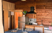 Binnenaanzicht van een knusse keuken en eethoek in een safaritent bij Flower Camping La Plage in Frankrijk.