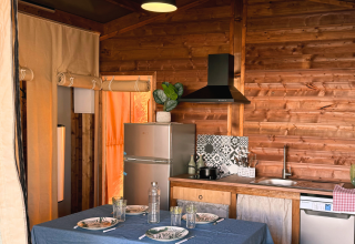 Indvendigt af en hyggelig køkken- og spisestue i en safari telt ved Flower Camping La Plage i Frankrig.
