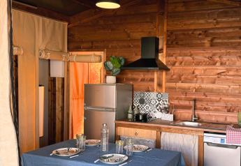 Indvendigt af en hyggelig køkken- og spisestue i en safari telt ved Flower Camping La Plage i Frankrig.