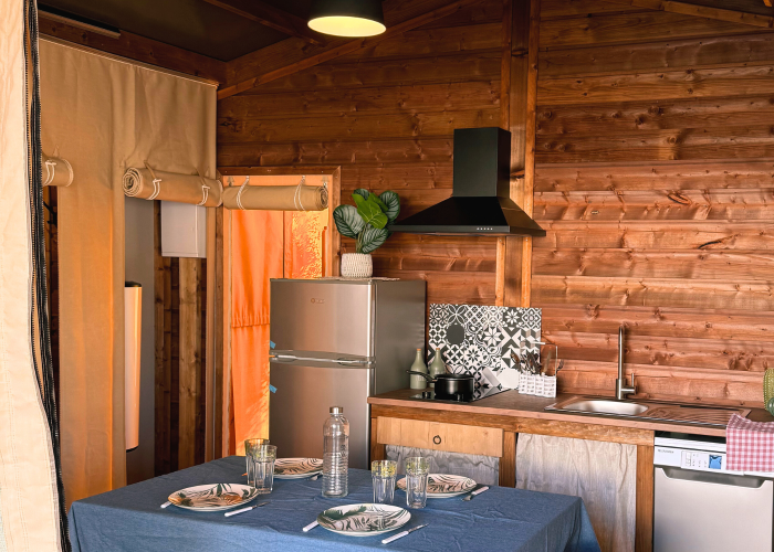 Vue intérieure d'une cuisine et salle à manger cosy dans une tente safari à Flower Camping La Plage en France.