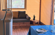 Indretning af en safaritelt med sofa, bord, kaktus og dækket spisebord på Flower Camping La Plage i Frankrig.