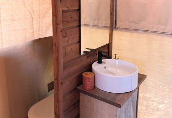 Badkamer in Cotton Flower Canvas Lodge Comfort bij Flower Camping La Plage, Frankrijk, met wastafel en hout.