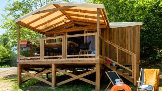 Cabaña de madera en Cosyflower Premium Lodge con terraza, tumbonas y un flotador naranja en el jardín.