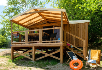 Houten lodge bij Cosyflower Premium met overdekte veranda, ligstoelen en een oranje zwemband buiten.