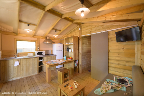 Vue intérieure du lodge Cosyflower Premium avec murs en bois, cuisine équipée, table et canapé.