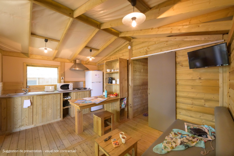 Interieur van de Cosyflower Premium-lodge met houten wanden, kitchenette, eettafel en bank.
