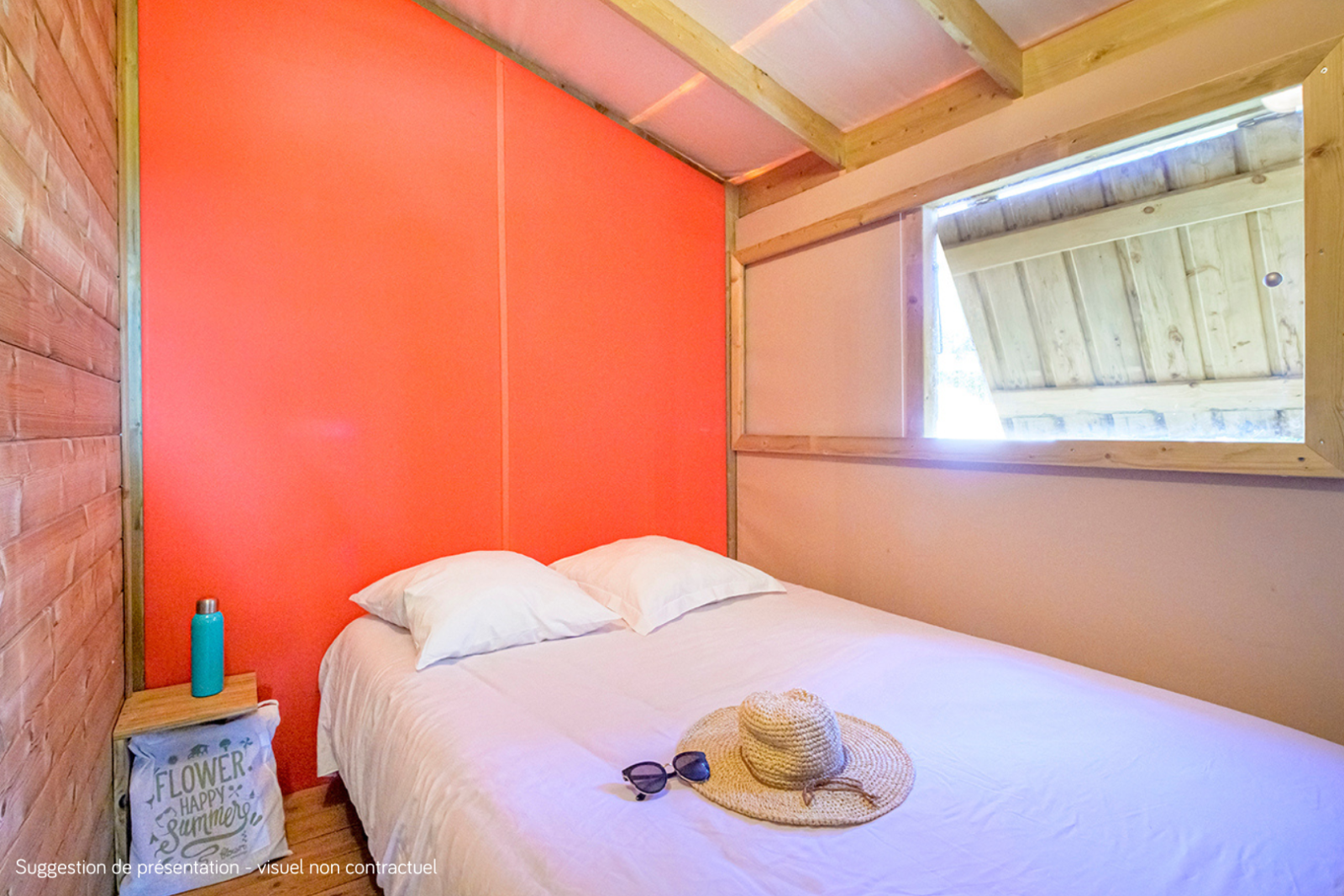 Lichte slaapkamer in de Cosyflower Premium lodge met tweepersoonsbed, strohoed en zonnebril op het bed.
