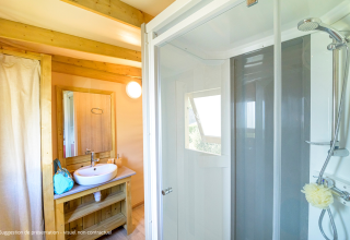 Modernes Badezimmer in der Cosyflower Premium-Lodge mit Dusche, Waschbecken und Holzverkleidung.
