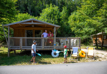 Dos niños juegan frente a una tienda safari Sweetflower Premium mientras dos adultos los observan desde la terraza.
