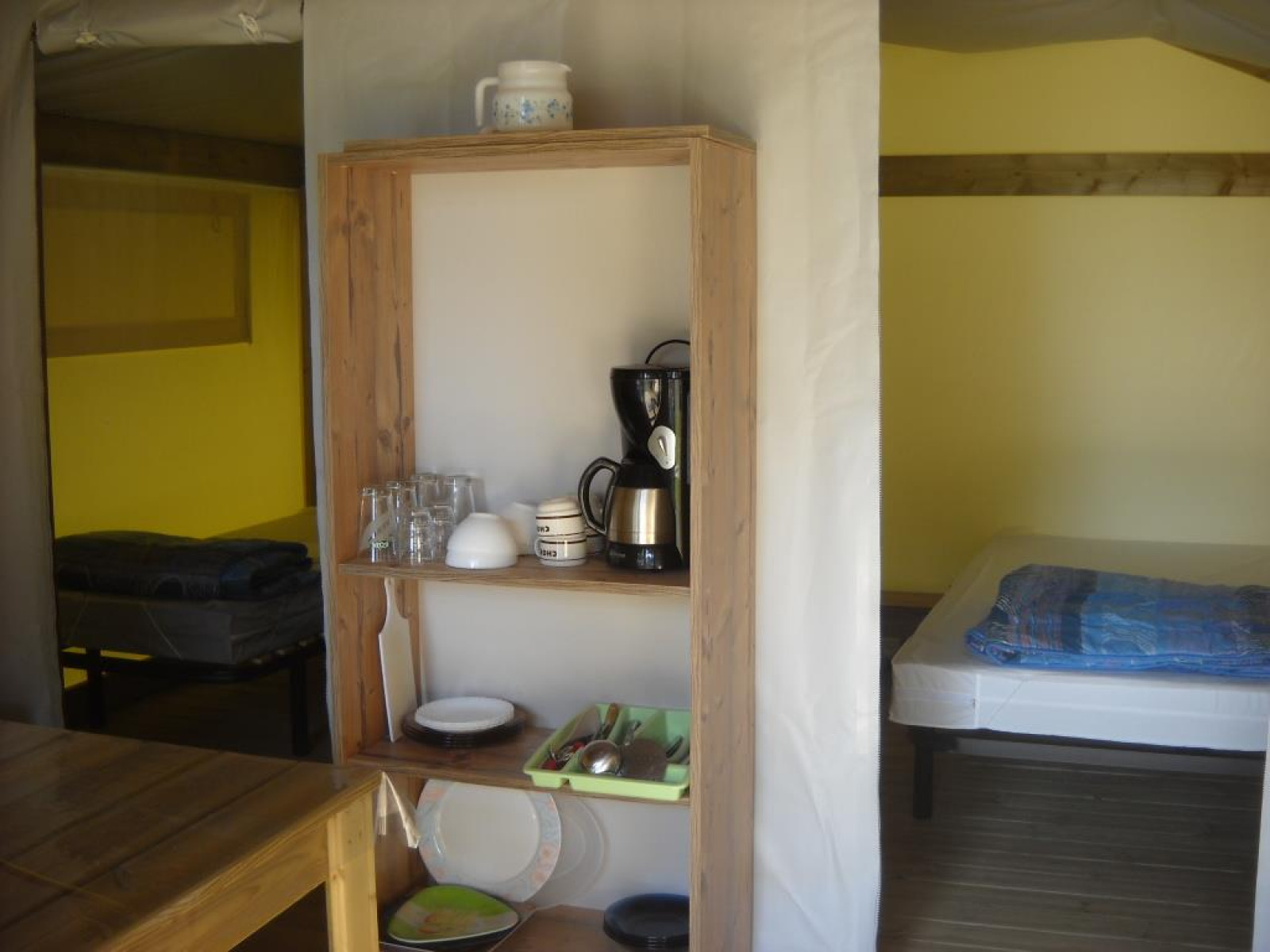 Interieur van een Freeflower Standard safaritent bij Flower Camping Cap Finistère met bed en keukenkast.