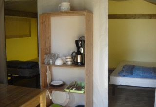 Interieur van een Freeflower Standard safaritent bij Flower Camping Cap Finistère met bed en keukenkast.
