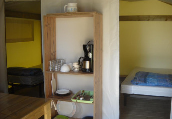 Interno di una tenda safari Freeflower Standard al Flower Camping Cap Finistère con letto e scaffale cucina.