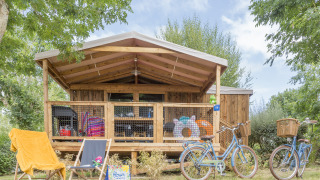 Outdoor view of Cosyflower Premium lodge featuring bicycles, deck chairs, and a wooden front porch.