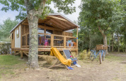 Buitenaanzicht van een Cosyflower Premium lodge bij Flower Camping Cap Finistère in Frankrijk, met fietsen en stoelen.