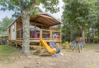 Buitenaanzicht van een Cosyflower Premium lodge bij Flower Camping Cap Finistère in Frankrijk, met fietsen en stoelen.