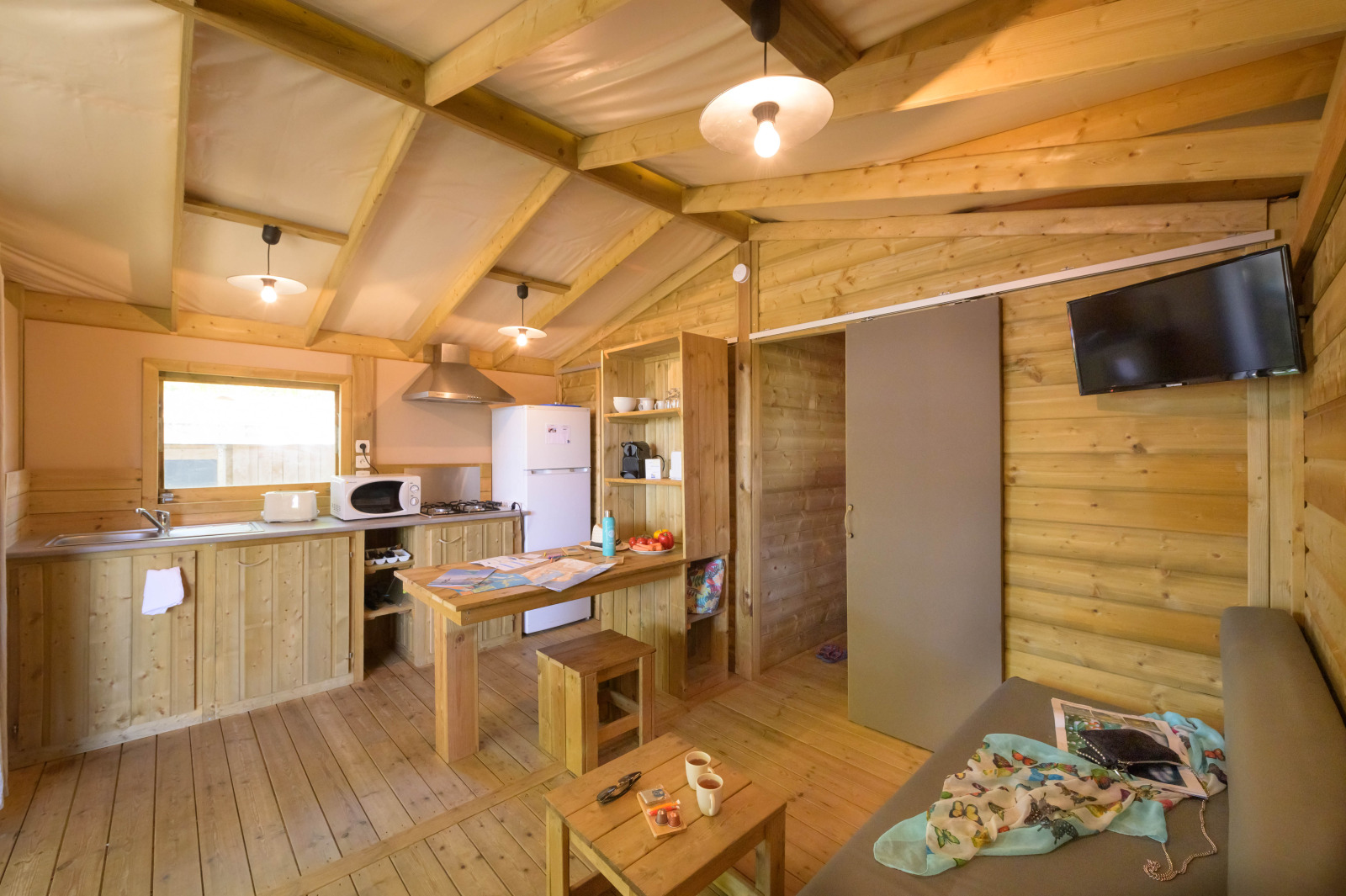 Interieur van een Cosyflower Premium glamping-accommodatie met houten meubels, keuken en zithoek.