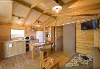 Vista interior de un alojamiento glamping Cosyflower Premium con muebles de madera, cocina y sala de estar.