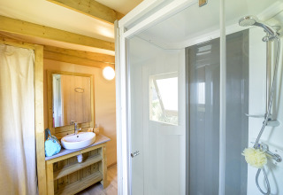 Moderne badkamer met douche en houten wastafeltafel in het glampingverblijf Cosyflower Premium.