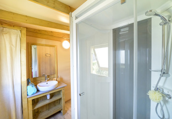 Moderne badkamer met douche en houten wastafeltafel in het glampingverblijf Cosyflower Premium.