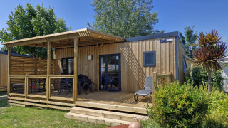 Outdoor view of a Homeflower premium lodge with wooden deck, garden furniture, and green plants.