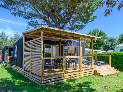 Lodge Homeflower premium con terrazza in legno a Flower Camping Cap Finistère, Francia, circondato dal verde.