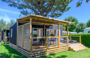 Homeflower premium lodge met houten terras bij Flower Camping Cap Finistère in Frankrijk, omgeven door groen.