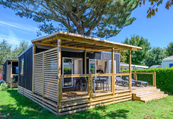 Homeflower premium lodge met houten terras bij Flower Camping Cap Finistère in Frankrijk, omringd door natuur.