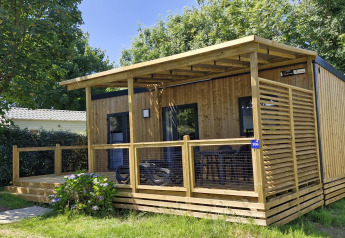 Gezellige houten Homeflower Premium lodge met overdekt terras en tuin, omringd door groen en bomen.