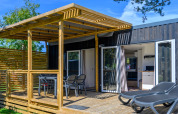 Buitenterras met ligstoelen en eettafel bij Homeflower premium lodge op Flower Camping Cap Finistère, Frankrijk.