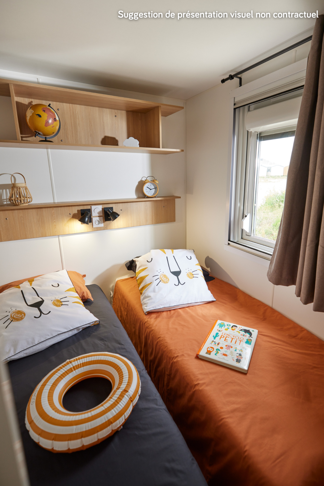Knusse glampingkamer met twee eenpersoonsbedden, dierenkussens, boek en raam met daglicht.