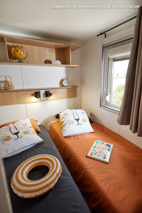 Cozy glamping bedroom with two single beds, animal face pillows, a book, shelves, and a bright window.