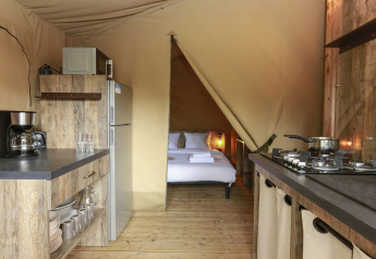 Interiør af komfortabelt safari telt med køkken og soveområde på Flower Camping Le Vieux Moulin i Frankrig.