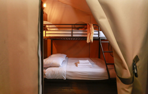Inside view of a safari tent with bunk beds and fresh towels at Tent Lodge Confort in France.