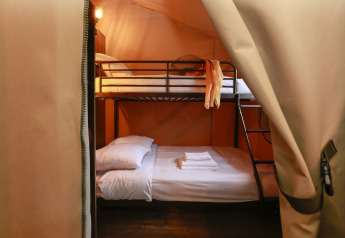 Interieur van een safaritent met stapelbed en verse handdoeken in Tent Lodge Confort, Frankrijk.