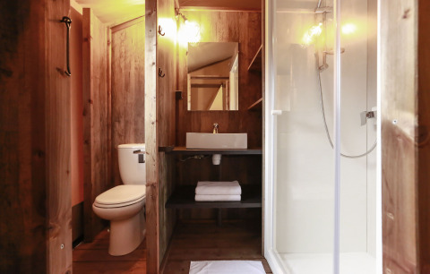 Badezimmer in einem Safari-Zelt mit WC, Waschbecken, Spiegel und Dusche im Flower Camping Le Vieux Moulin.