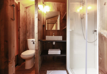 Bagno in una tenda safari lodge con WC, lavandino, specchio e doccia al Flower Camping Le Vieux Moulin in Francia.