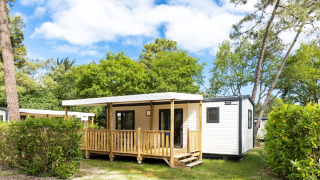 Außenansicht einer Stacaravan Premium Hütte mit überdachter Terrasse und zwei Badezimmern im Grünen.