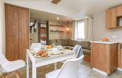 Espace salon-salle à manger moderne et lumineux dans la Stacaravan Premium, cuisine et meubles bois en France.