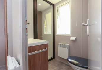 Bagno moderno in un alloggio glamping con finestra, WC, lavandino, specchio e luce naturale.