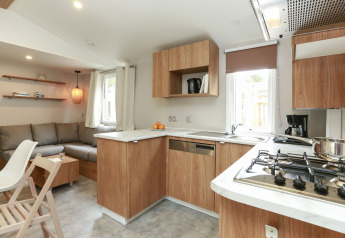 Cuisine moderne en bois et salon dans le Stacaravan Premium au Flower Camping Le Vieux Moulin en France.