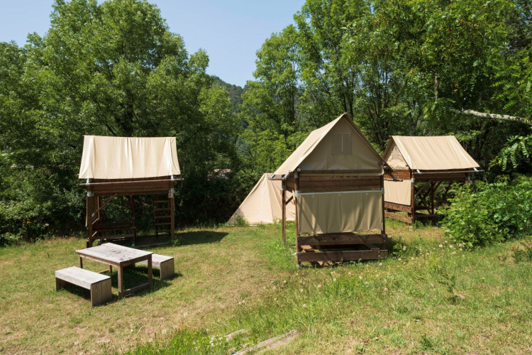 Standaard bivak op palen safari tents at Flower Camping Mas de Champel, France, surrounded by greenery.