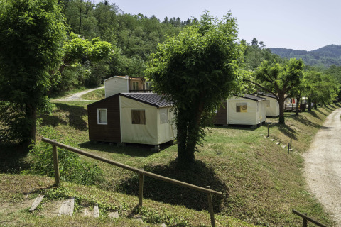 Canvas Mobile-Home Tithome bij Flower Camping Mas de Champel in Frankrijk, omgeven door bomen en heuvels.
